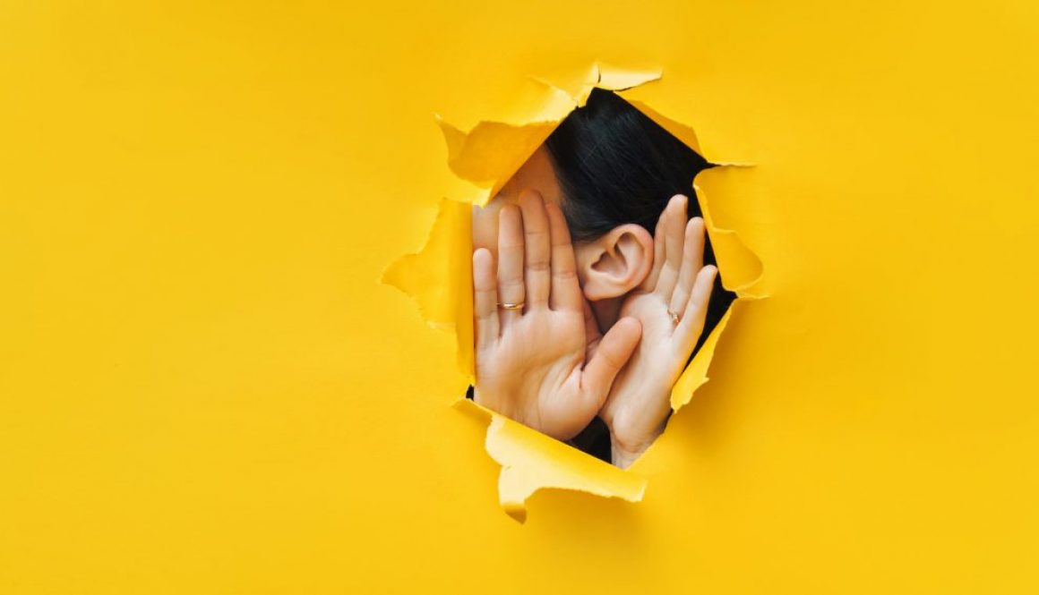 Female,Ear,And,Hands,Close-up.,Copy,Space.,Torn,Paper,,Yellow