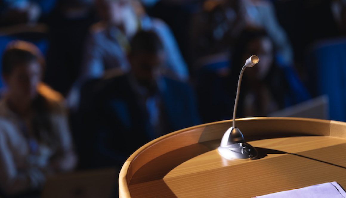 Close up of podium with speaker in auditorium konuşmacı ajansı seçimi