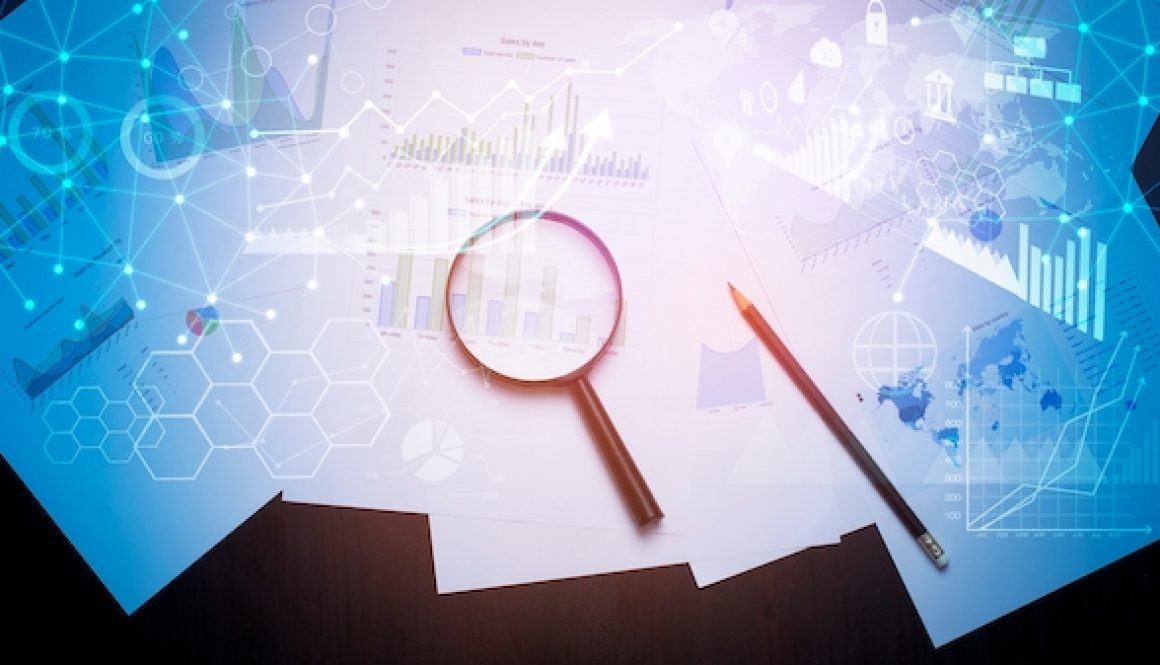 Magnifying glass and documents with analytics data lying on table