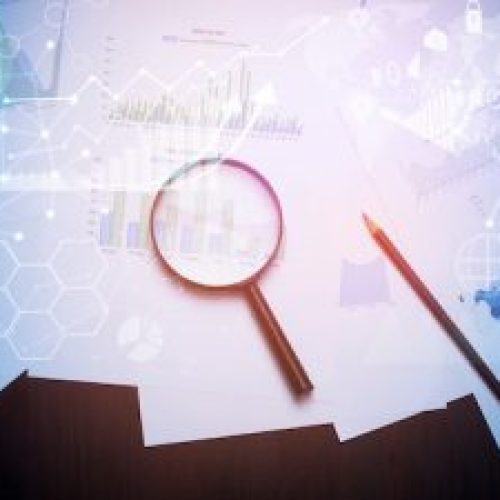 Magnifying glass and documents with analytics data lying on table