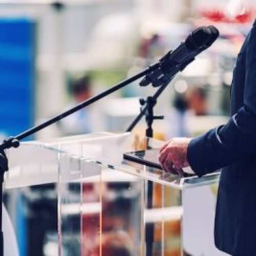Male Speaker Standing In Front Of Microphones