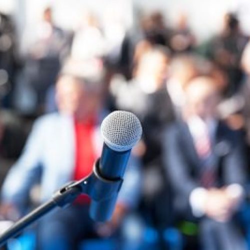 Microphone in focus against blurred audience Microphone in focus against blurred audience